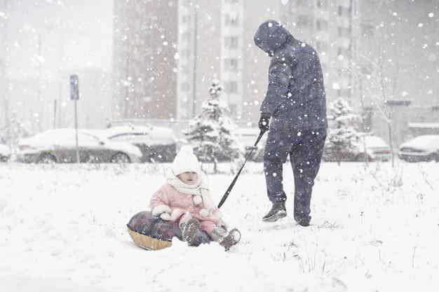 Dad takes little daughter on a tubing in a strong snow storm Premium Photo